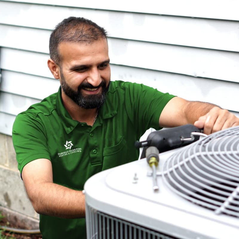 Technician in green shirt servicing outdoor AC unit
