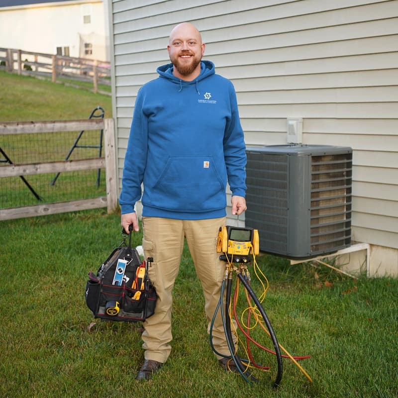 Technician standing outside with tool bag and gauges by AC unit
